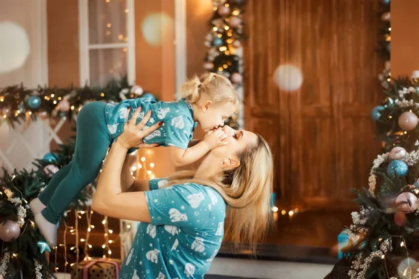 Boldog szőke anya feldobja a lányát a levegőbe. Női csók csecsemő. Karácsony — Stock Fotó
