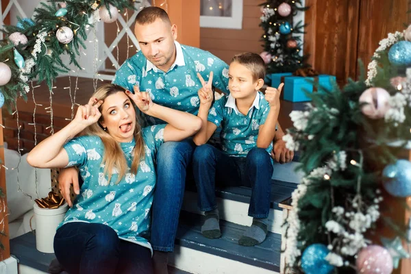 Család - anya, apa és fia - érezzék jól magukat karácsonykor. A nő arcokat és grimaszokat vág. A fiú is próbál vicces lenni. A férj félreértéssel néz a feleségre. — Stock Fotó