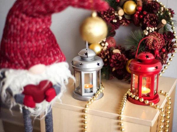 Lanternas de Natal vintage Vermelho e cinza com velas em chamas e anão cinza em chapéu vermelho com coração vermelho nas mãos. Decorações de Natal acolhedoras com contas douradas e bolas. Árvore de Natal no fundo . — Fotografia de Stock