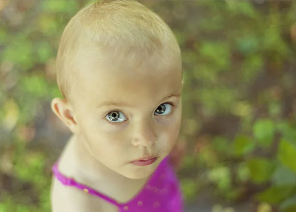 Primer plano retrato de niña de 3 años en vestido de verano rosa con el pelo muy corto y grandes ojos hermosos. No todas las niñas tienen el pelo largo y es normal. Cara seria — Foto de Stock