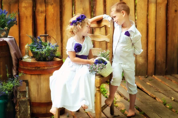 Small boy and girl in white clothes in rustic style decorations. Eco family. Organic and ecological lifestyle in childhood. Brother and sister look at each other. Summertime — Stock Photo, Image