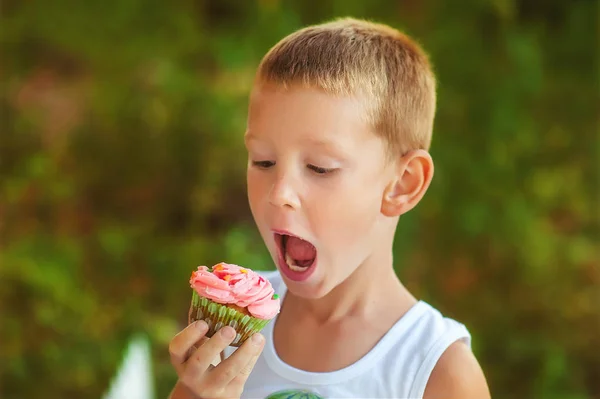 5 anos de idade menino comer caseiro sem glúten saudável cupcake. Cozimento natural orgânico para crianças. Delicioso bolinho na festa de aniversário. Crianças na festa de aniversário ao ar livre na hora de verão. Miúdo faminto — Fotografia de Stock