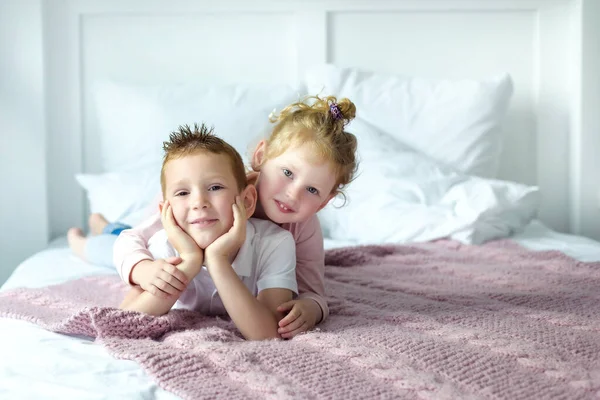 Brother and sister boy and girl play together in bedroom. Little girl lay on her brother back. Happy childhood in cozy family circle. Siblings playing together. Space for text