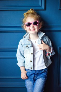 Kot ceketli, kot pantolonlu, mavi stüdyoda pembe gözlüklü, dört yaşında, kıvırcık, sarışın, gülen bir kız. Çocukluğundaki hippi yaşam tarzı. Modaya uygun bir çocuk. Moda çocuk arıyor.