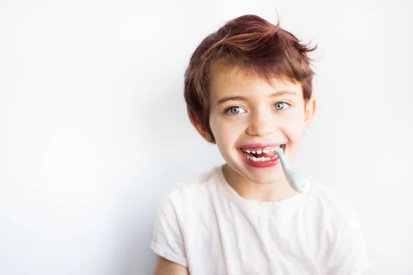 Ağzında mavi ve beyaz diş fırçası olan gülümseyen çocuğun yatay portresi. Çocukluktan kalma diş ve sağlık hizmetleri. Gülümseyen gülen yüzün dişlerini değiştirmek sağlıklı. Beyaz arka plan. Boşluğu kopyala — Stok fotoğraf