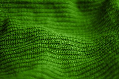 Arkaplan olarak katlanmış parlak yeşil yün kazak kumaşı. Yatay yeşil arka plan deseni. Uzayı metin için kopyala. Tasarım.