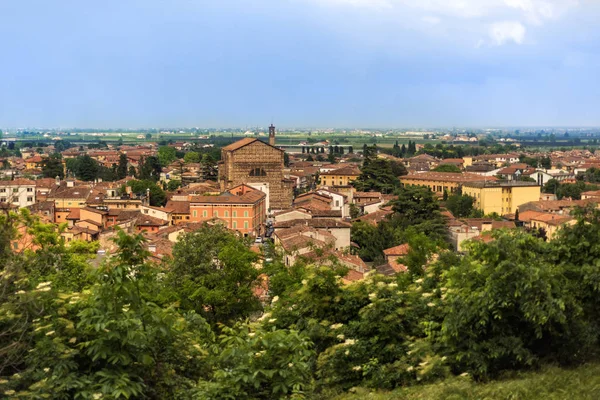 View on the roofs of Bergamo, Lombardy, Italy. Cloudy light blue sky above red roofs of medieval city. Spring in italian city. City landscape with rooftops and blooming trees. — Stock Photo, Image