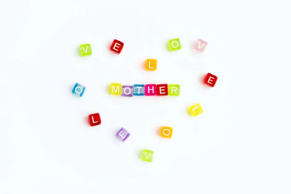 Top view on sign mother from small colorful letters and heart from colored letters with text love. Mother day card. Woman day. 8 march. Mothers day concept. White background. — Stock Photo, Image