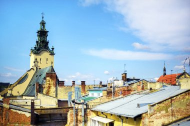 Ukrayna 'nın batısındaki Lviv şehrindeki çatılar, eski taş duvarlar ve tuğla duvarlar ve katolik kilise manzarası. Kablolar, binalar ve mavi yaz gökyüzü ile kavramsal şehir manzarası