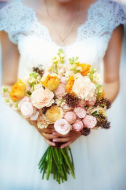 Düğün gününde gelinin ellerinde pembe ve sarı güller olan güzel bir düğün buketi. Düğün dekoru. Gelin buketi için fikir. Kadınların elinde çiçekler.