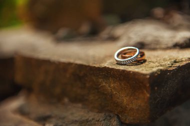 Kavramsal karanlık taş arka planda alyanslar. Düğün günü gelin ve damat yüzüğü. Evlilik için dekorasyon. Düğün dekoru