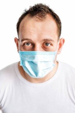 Mavi tıbbi maskeli, koronavirüsten korkan korkmuş beyaz adamın dikey yakın plan portresi. Soğuk mevsimde sağlık hizmeti. Covid-2019 hastalığı. Tıbbi bakım.
