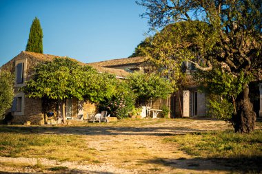 Fransa 'nın Provence kentindeki çiftliğin arka bahçesinde, sıcak yaz sabahında açık mavi gökyüzüyle Luberon Tepesi' nin arka planında eski bir taş atölyesi. Turizm beldesi Provence