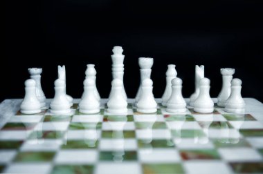 Beyaz satranç figürlerinin mermer yeşil ve beyaz satranç masasında düzenlenmesi. İş dünyasının liderliği doğru başlangıç pozisyonudur. Satranç masası iş konsepti gibidir..