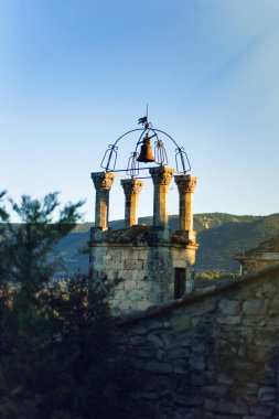 Fransa 'nın en güzel köylerinden biri olan Lacoste, Vaucluse, Provence, Fransa' daki eski ortaçağ köyü Lacoste 'deki ortaçağ çan ve saat kulesinin dikey günbatımı manzarası. Seyahat.