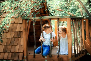 Küçük oğlan ve kız, Forest Park 'taki ağaç evde oyun parkında aktif çocuklar yaz güneşli bir günde tırmanış parkında eğlenen çocuklar. Ekolojik oyun alanı.