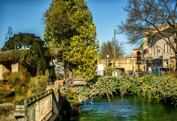Wheel of water mill in Medieval village L\'Isle-sur-Sorgue, Vaucluse, Provence, France. Famous Sorgue river with green water and provencal houses. Provence travel tourism destination. Summer vacation