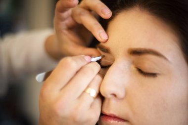 Sahne arkasına yakın çekim: Profesyonel makyaj sanatçısı kaş düzeltmesi yapıyor. Makyaj sanatçısı kozmetik uzmanı. Güzel kadın yüzü. Makyaj ayrıntıları.