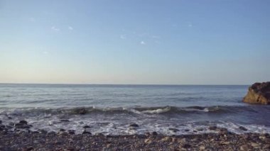 Denizin kayalık kıyılarında. Dalgalar gürültüyle kayalık bir kıyıya yuvarlanır. Deniz kenarında gün doğumu. Güzel deniz manzarası. Fırtınalı bir okyanusun kayalık kıyısı. Dalgalar kıyıya vuruyor.