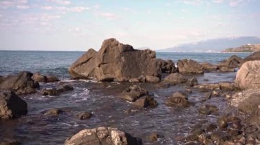 Denizin kayalık kıyılarında. Dalgalar gürültüyle kayalık bir kıyıya yuvarlanır. Deniz kenarında gün doğumu. Güzel deniz manzarası. Fırtınalı bir okyanusun kayalık kıyısı. Dalgalar kıyıya vuruyor.