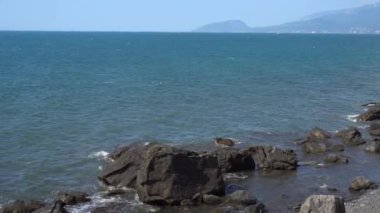 Denizin kayalık kıyılarında. Dalgalar gürültüyle kayalık bir kıyıya yuvarlanır. Deniz kenarında gün doğumu. Güzel deniz manzarası. Fırtınalı bir okyanusun kayalık kıyısı. Dalgalar kıyıya vuruyor.