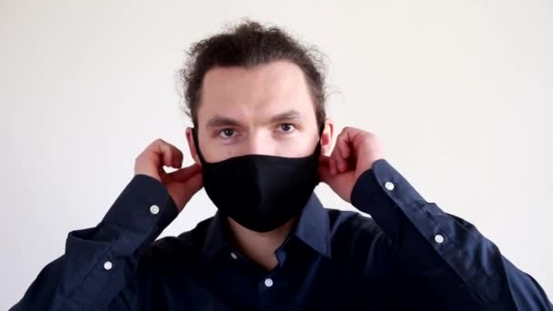 Ein junger bärtiger Mann nimmt seine Schutzmaske ab. Das Konzept zur Beendigung der Pandemie und Ausweg aus der Quarantäne — Stockvideo