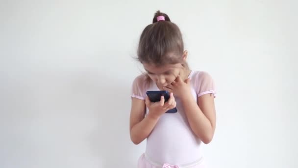 Petite fille regardant dans le téléphone, bavardant avec ses amis en ligne. Communication en ligne et concept de blogging. Un enfant regarde une vidéo au téléphone — Video