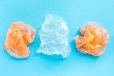 Dünya 'yı ve ekoloji kavramını kurtar. Flatlay, mavi arka planda renkli plastik poşetlerle kaplıydı. Çevresel koruma ve çöplerin ayrı sıralanması.