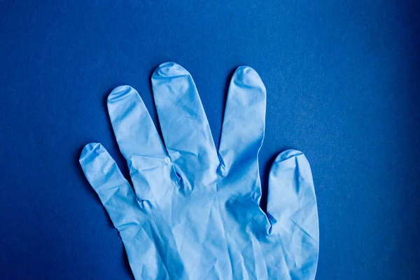 Prevention from of coronavirus. Close-up medical protective glove on a blue background. Protection against danger COVID-19 — Stock Photo, Image