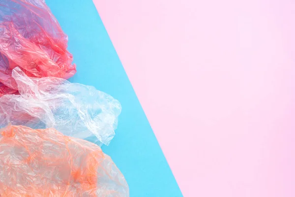 Gyűrött műanyag zacskók kék és rózsaszín háttér másolási fázissal. Szemétválogatás és konzerválás ökológia koncepció. Lapos összetétel. — Stock Fotó