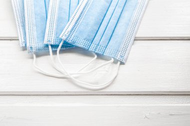 Beyaz ahşap arka planda mavi koruyucu tıbbi maskeleri kapatın. Ulaşım ve mağazaları ziyaret etmek için koruyucu bir maske gereklidir. Coronavirus önleme konsepti. Düz yatıyordu.
