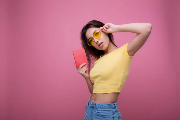 Beautiful portrait young asian woman wear sunglasses on head smile confident enjoy summer holiday isolated blue background, model girl fashion hipster holding passport, travel concept. — Stock Fotó