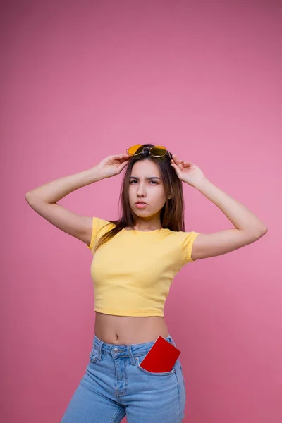 Beautiful portrait young asian woman wear sunglasses on head smile confident enjoy summer holiday isolated blue background, model girl fashion hipster holding passport, travel concept. — Stock Fotó