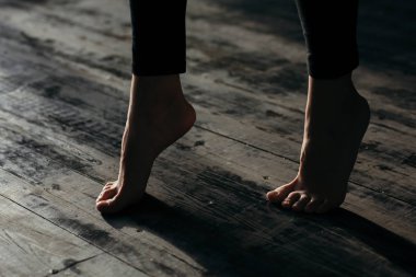 Female feet walking on warm heated floor close up view, barefoot girl legs going on hardwood living room wooden flooring at modern home house, domestic underfloor heating concept, close up rear view