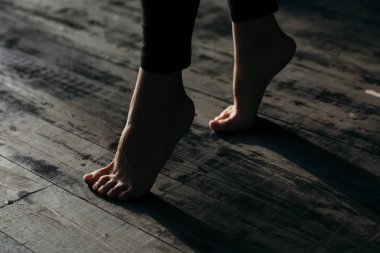 Female feet walking on warm heated floor close up view, barefoot girl legs going on hardwood living room wooden flooring at modern home house, domestic underfloor heating concept, close up rear view