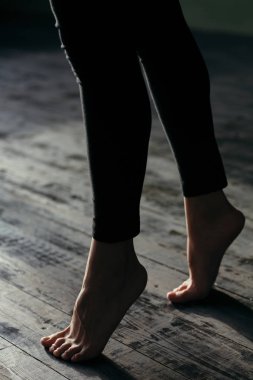 Female feet walking on warm heated floor close up view, barefoot girl legs going on hardwood living room wooden flooring at modern home house, domestic underfloor heating concept, close up rear view