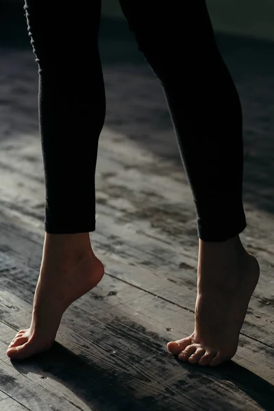 Female feet walking on warm heated floor close up view, barefoot girl legs going on hardwood living room wooden flooring at modern home house, domestic underfloor heating concept, close up rear view