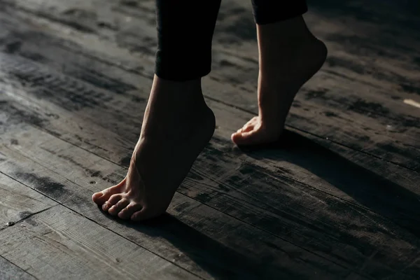 Female feet walking on warm heated floor close up view, barefoot girl legs going on hardwood living room wooden flooring at modern home house, domestic underfloor heating concept, close up rear view