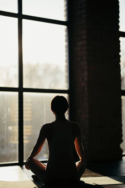 Jonge aantrekkelijke vrouw beoefenen van yoga in de buurt van verdieping venster, permanent in Bridge oefening Urdhva Dhanurasana pose, uit te werken, het dragen van sportkleding, grijze broek, beha, overdekt volledige lengte, interieur — Stockfoto