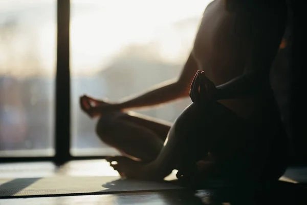 Meisje zittend op een yoga mat in lotuspositie. zonlicht van het raam naar de studio — Stockfoto