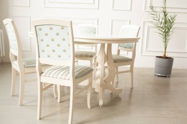 Klasik bir iç mekanda akşam yemeği için beyaz masalar ve sandalyeler. Masada rahat oturmak için döşenmiş sandalyeler.