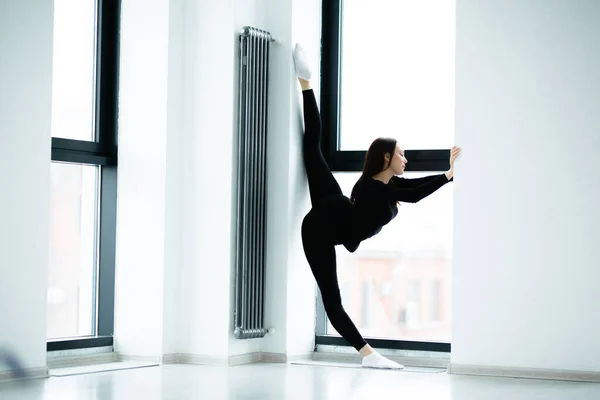 Schöne athletische Frau in Sportbekleidung beim Stretching der Beine am Fenster — Stockfoto