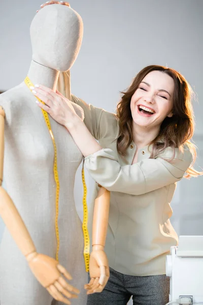 Playful seamstress measures the thickness of the neck of a mannequin — ストック写真