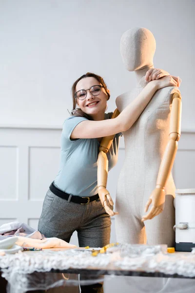 Vrouwelijke mode-ontwerper genieten van haar werk en kijken naar een etalagepop met liefde — Stockfoto
