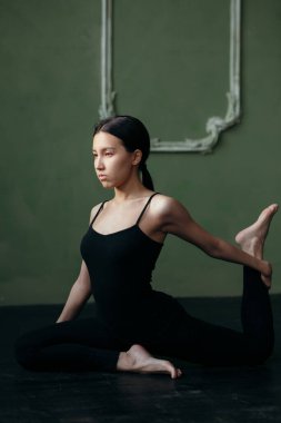 Kız esneme egzersizi yapıyor. Yoga sınıfı siyah spor giyim..