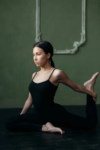 Fata face exerciții de întindere. Clasa de yoga în îmbrăcăminte sport neagră . — Fotografie, imagine de stoc