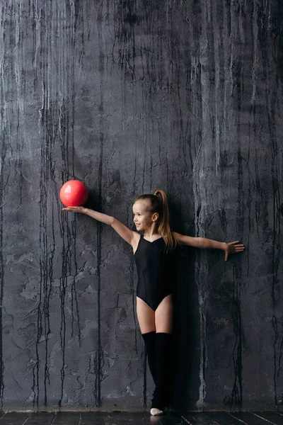 Foto de Studio shot of attractive little gymnast girl of wearing black  leggings and a bathing suit with a green jump rope on a white background,  full length. do Stock