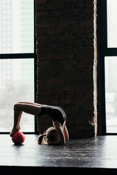 The girl does gymnastics with a red ball near the window. — Φωτογραφία Αρχείου
