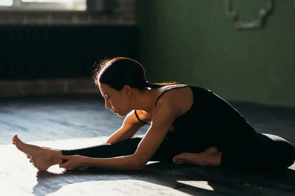 Meisje is aan het stretchen. Yoga klasse in zwarte sportkleding. — Stockfoto