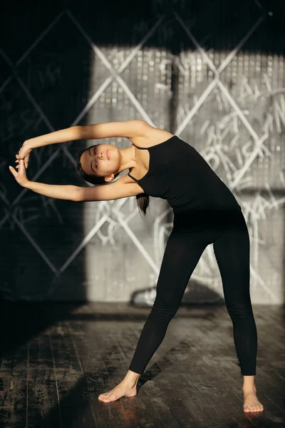 Fata face exerciții de întindere. Clasa de yoga în îmbrăcăminte sport neagră . — Fotografie, imagine de stoc